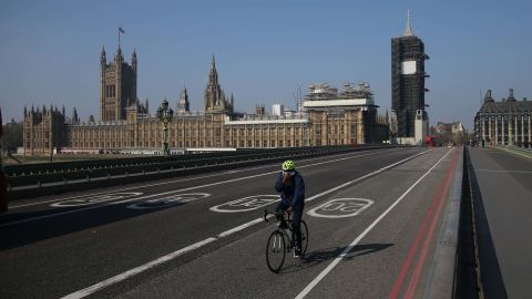 A cyclist crosses a near-empty Westminster Bridge with the Houses of Parliament in the background in central London on April 9, 2020. - British Prime Minister Boris Johnson on Thursday began a fourth day in intensive care